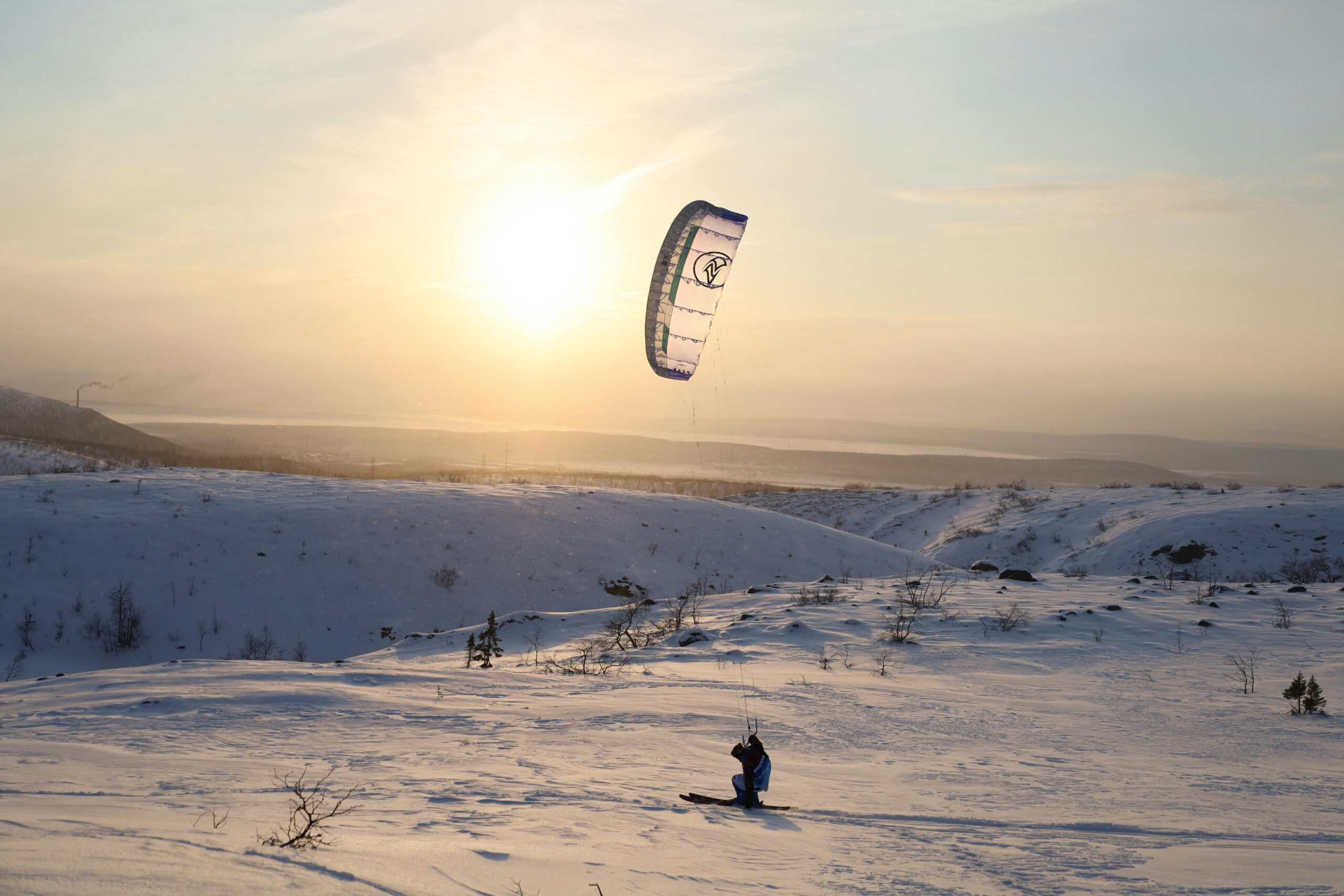 Experience the thrill of kiteboarding against a winter sunset backdrop in the snowy mountains of Kirovsk.