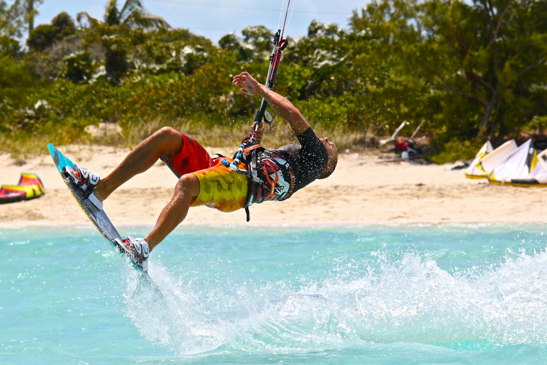 Exciting kiteboarding maneuver captured in action on a sunny beach, showcasing thrill and energy.